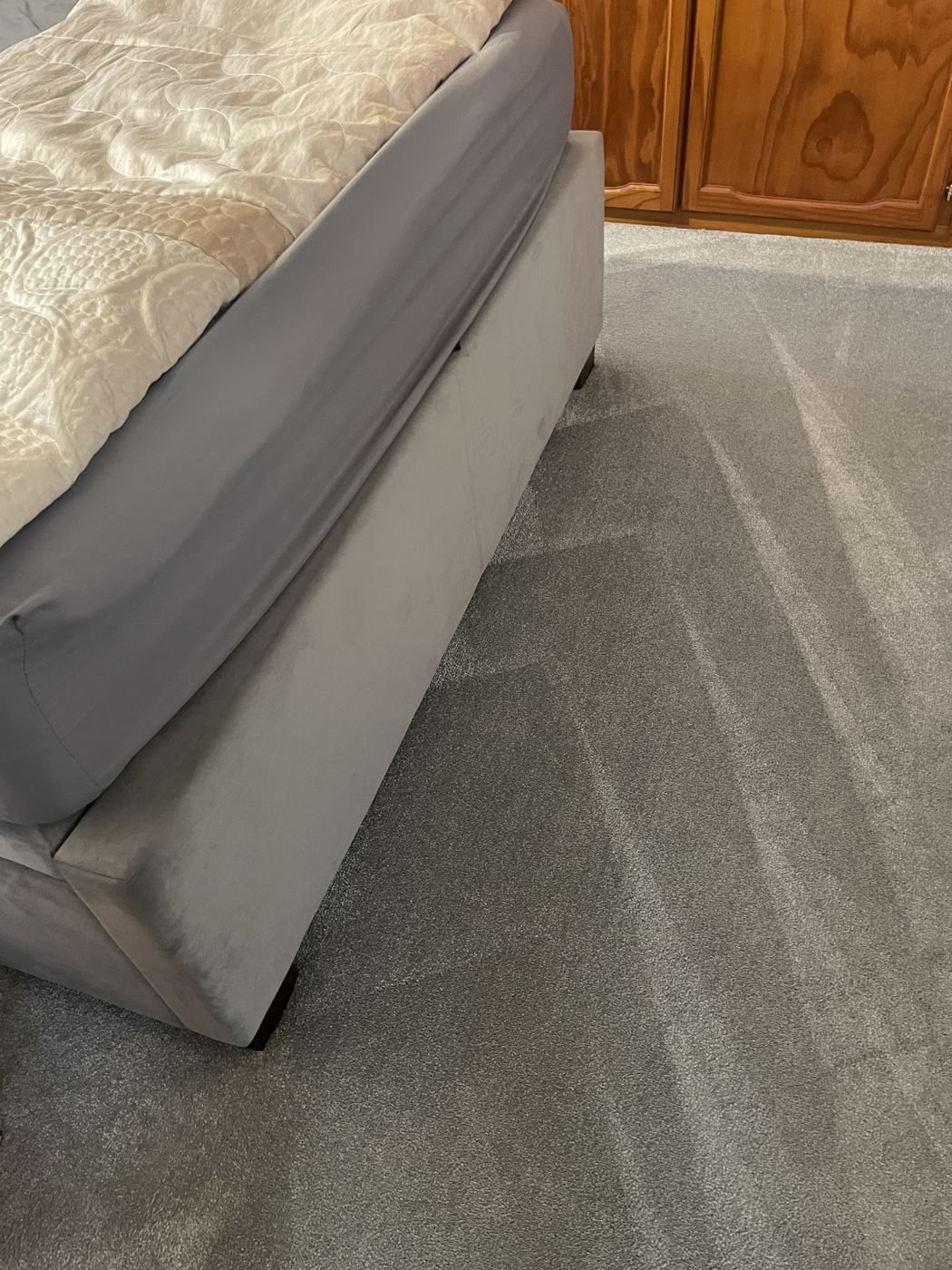 Grey carpet fitted around a bed